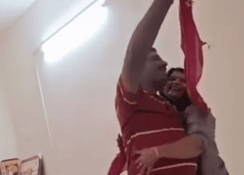 A man and woman are dancing together in a warmly lit room, enjoying a moment of connection and joy.