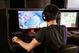 A man focused on playing video games, using two monitors for an immersive gaming experience.