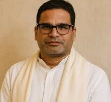 A man with glasses wearing a white shirt, looking directly at the camera with a neutral expression.