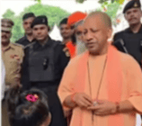A person in an orange robe engages with a child in an outdoor setting, surrounded by security personnel, conveying a tone of attentiveness and calm.