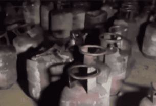 A dimly lit room filled with numerous gas cylinders, showing signs of rust and wear, creating a sense of neglect and potential danger.