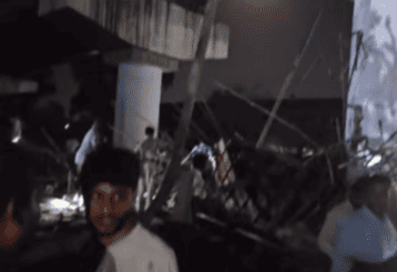 "Debris and collapsed structures at night with emergency workers and onlookers, conveying chaos and urgency in a disaster scene."